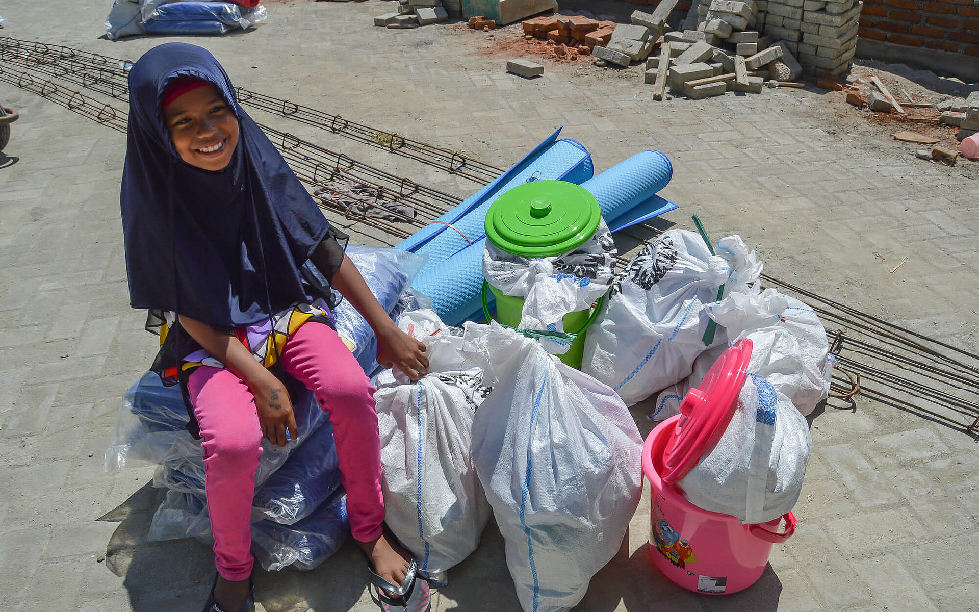 Ein Mädchen sitzt auf Hilfsgütern, die ihre Familie nach dem Tsunami von CARE erhalten haben
