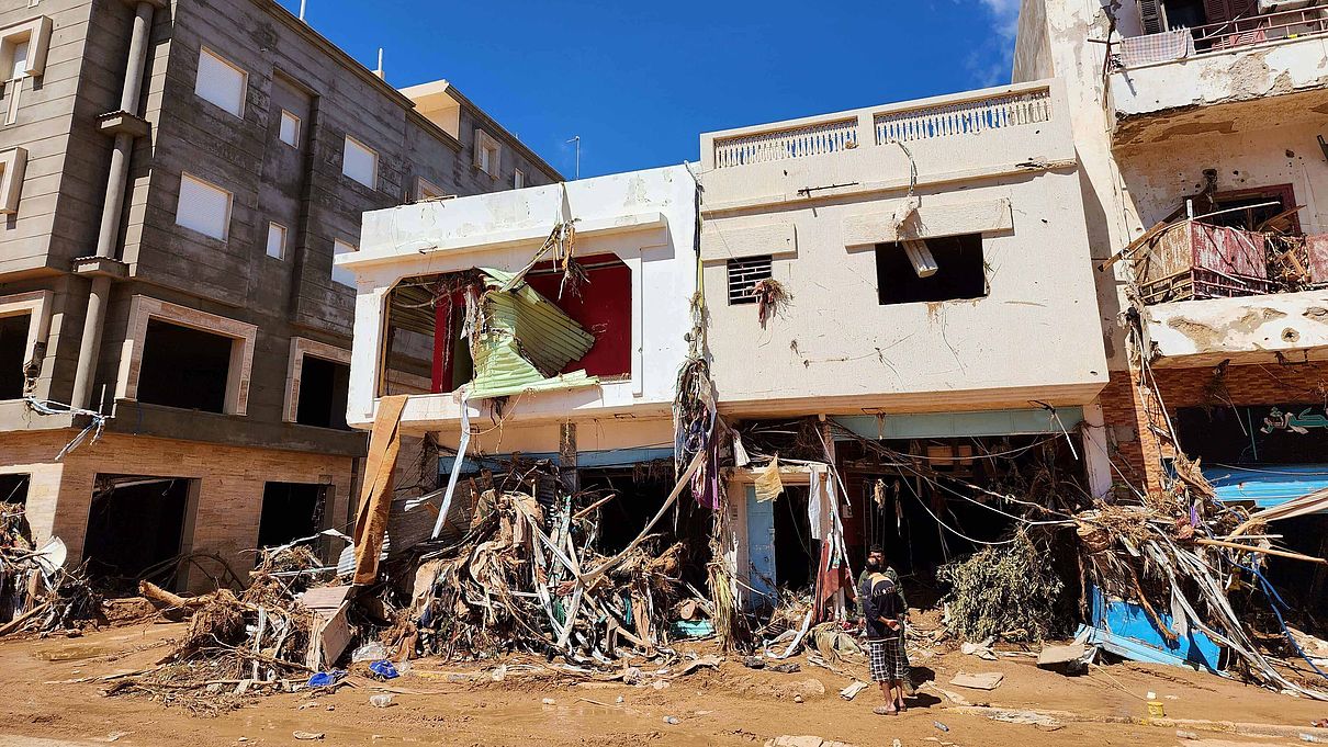 Zwei Männer stehen vor stark verwüsteten Häusern nach den verheerenden Überschwemmungen in Libyen.