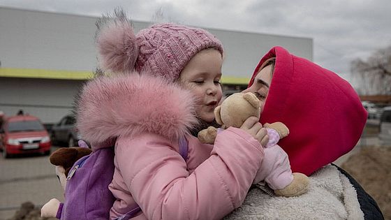 Ukrainische Geflüchtete hebt Mädchen hoch