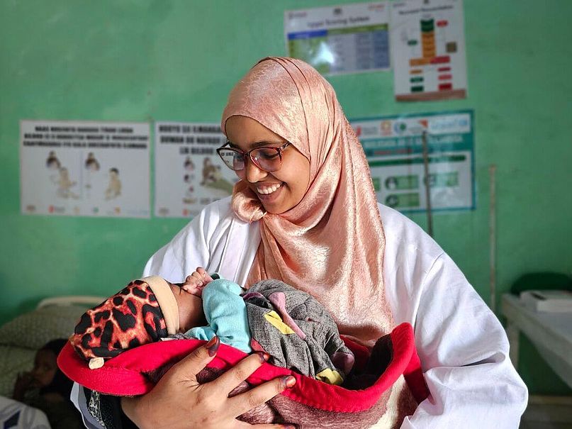 Hayat hält Bushra Die Hebamme Hayat hält das Baby Bushra auf dem Arm.