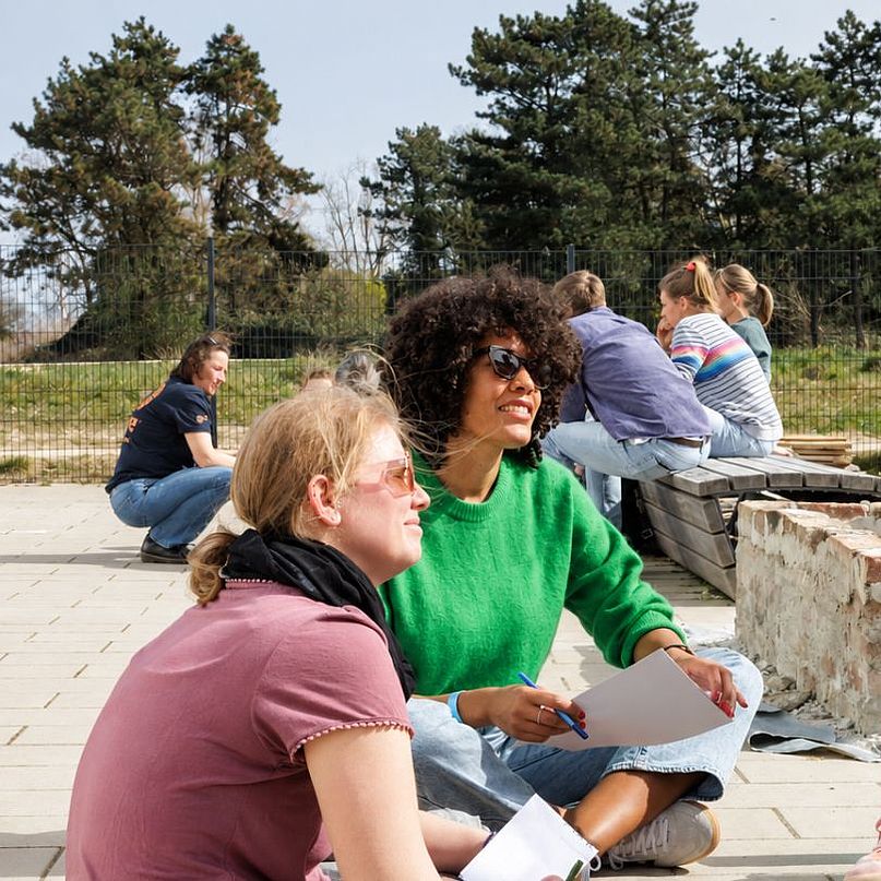 Lehrerinnen sitzen zusammen Lehrerinnen sitzten draußen und beraten sich.