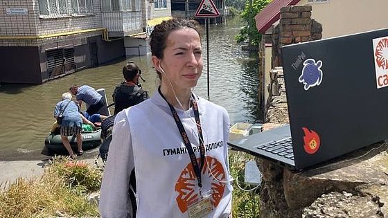 Eine CARE-Helferin steht vor ihrem Laptop im Überschwemmungsgebiet.