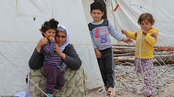Aufnahme einer Großmutter im Irak, umringt von ihren Enkelkindern vor einem Zelt.
