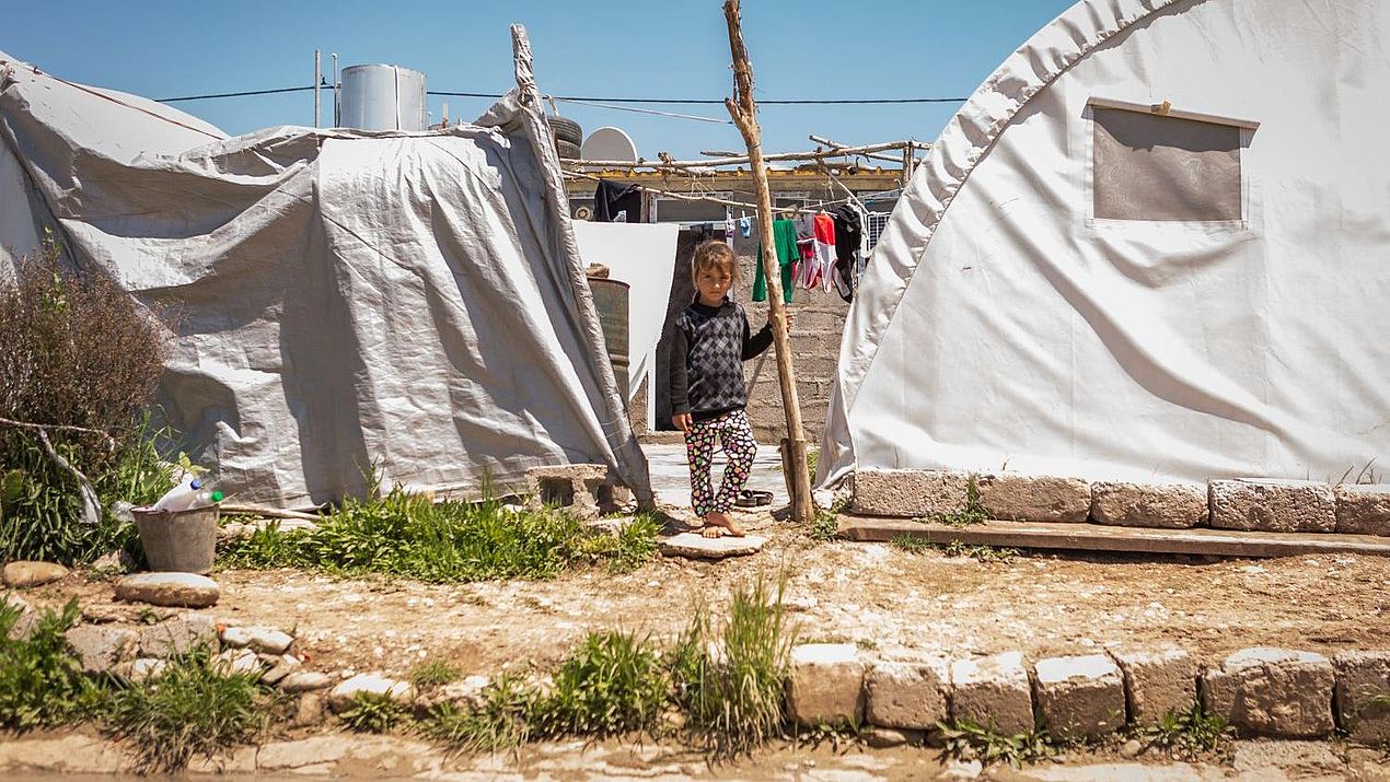 Ein Kind steht vor einem Zelt im Camp.