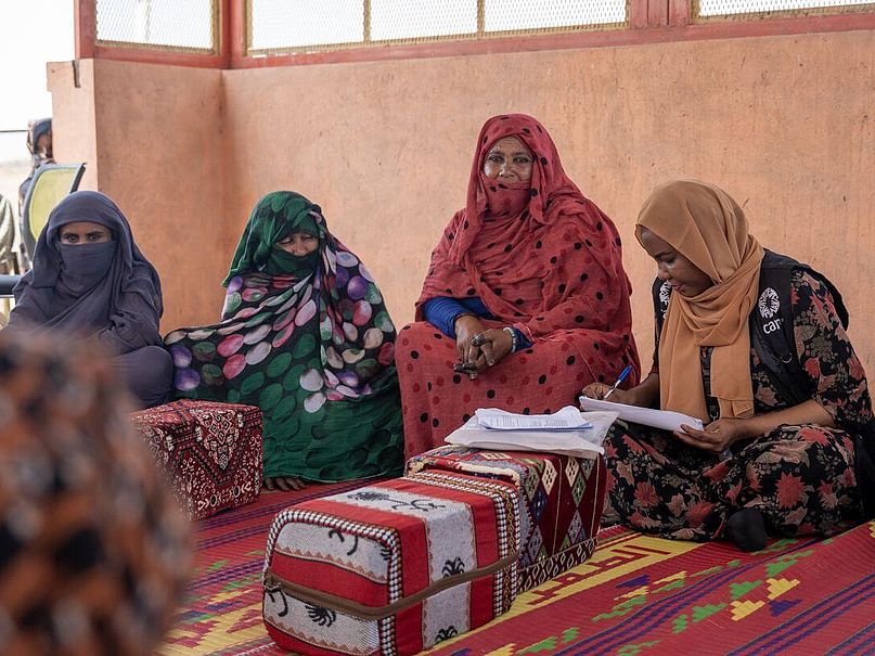 Frauengruppe im Ostsudan sitzt zusammen Die Frauen einer Frauengruppe im Sudan sitzen zusammen und fuehren Buch ueber ihre Aktivitaeten.