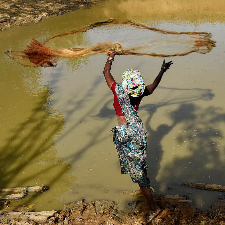 Eine Frau wirft ihr Netz zum Fischen aus.