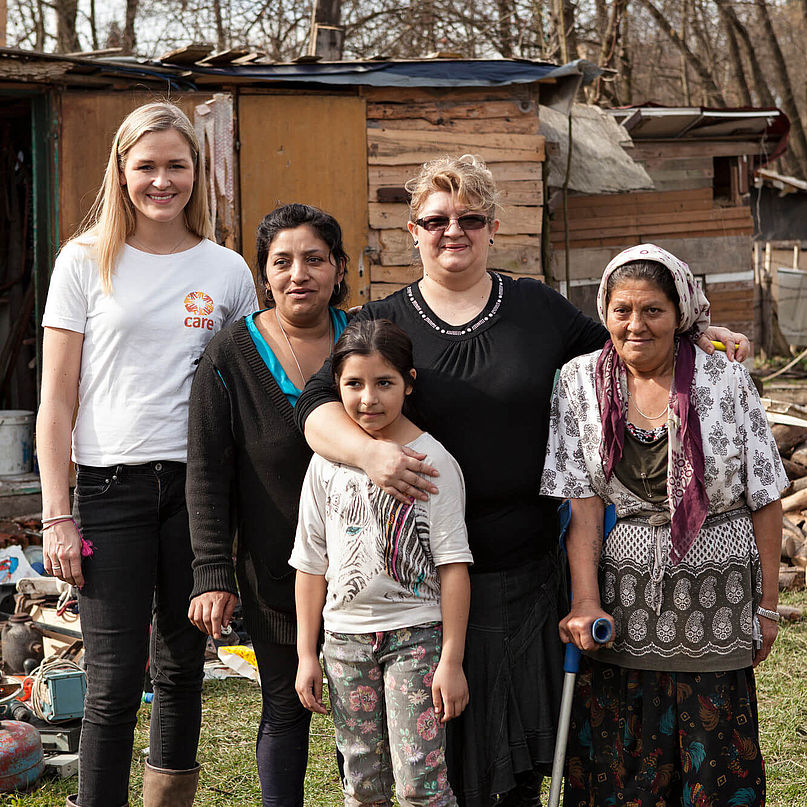 Eine CARE-Mitarbeiterin steht neben einer Roma-Familie