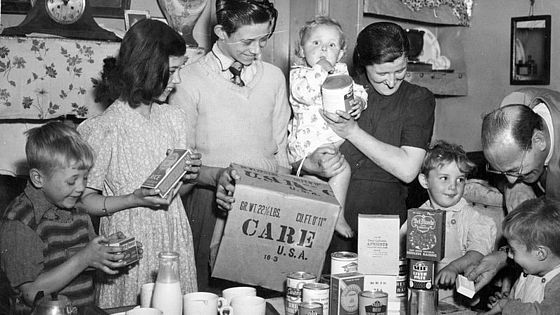 Eine Familie in der Nachkriegszeit packt ein CARE-Paket aus