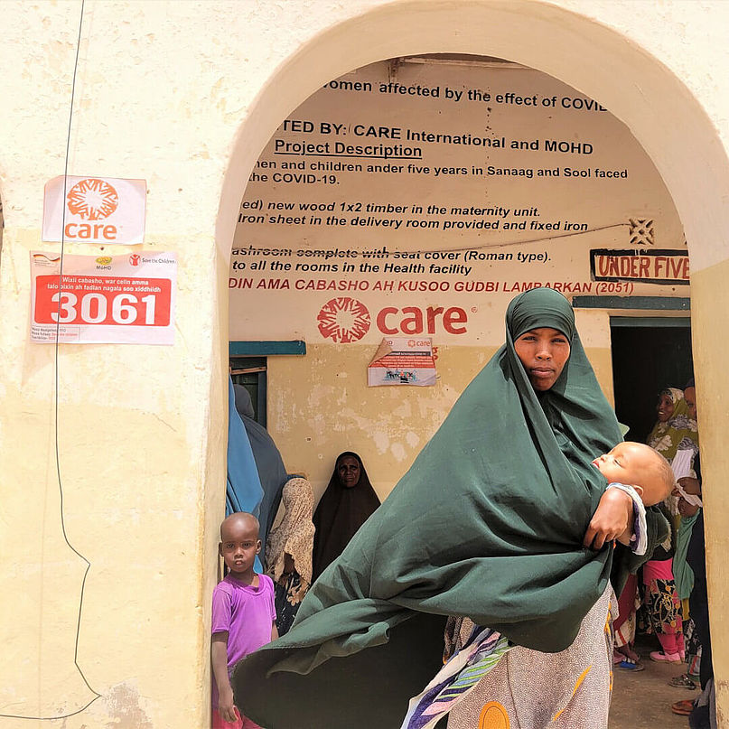 Hodan steht mit ihrem Baby vor der CARE-Gesundheitsklinik.
