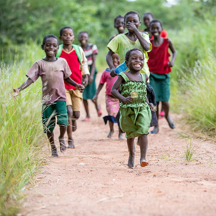 Kinder in Sambia laufen und lachen glücklich