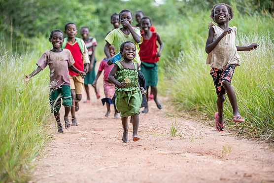 Kinder in Sambia laufen und lachen glücklich