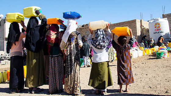 Jemenitische Frauen tragen Wasser.