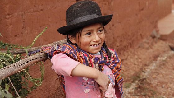 Ein Mädchen lächelt und trägt einen traditionellen Peruanischen Hut