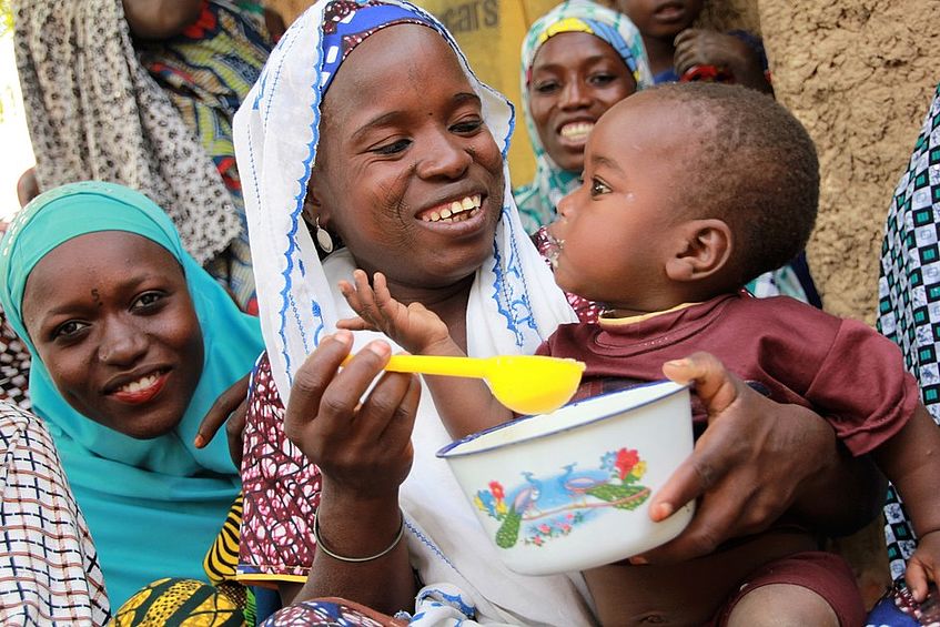 Eine Frau füttert ihren Säugling mit Brei aus Ziegenmilch.