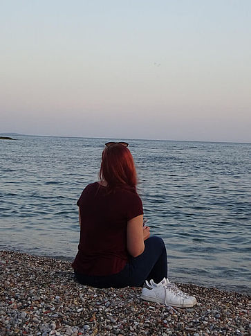 Ein junges Mädchen schaut in den Sonnenuntergang am Mittelmeer.