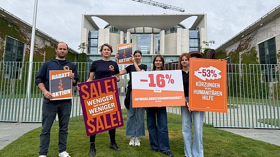 Eine Gruppe CARE-Mitarbeitende halten Demoschilder vor dem Kanzleramt.