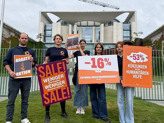 CARE-Mitarbeitende vor Kanzleramt Eine Gruppe CARE-Mitarbeitende halten Demoschilder vor dem Kanzleramt.