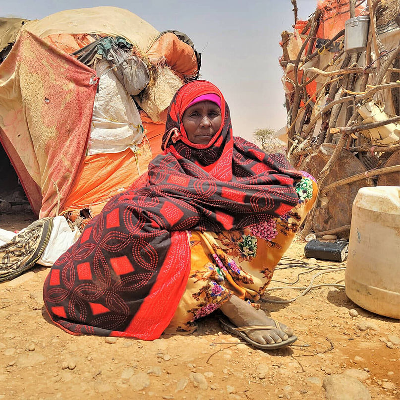 Aisha aus Somalia sitzt vor ihrem Zelt.