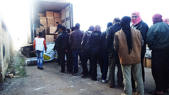 In einer Stadt in der südsyrischen Provinz Dara wartet eine Gruppe Männer auf die Verteilung von Hilfsgütern.