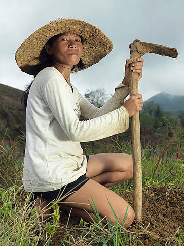 Eine Frau kniet auf einem Feld und hält ihr Werkzeug
