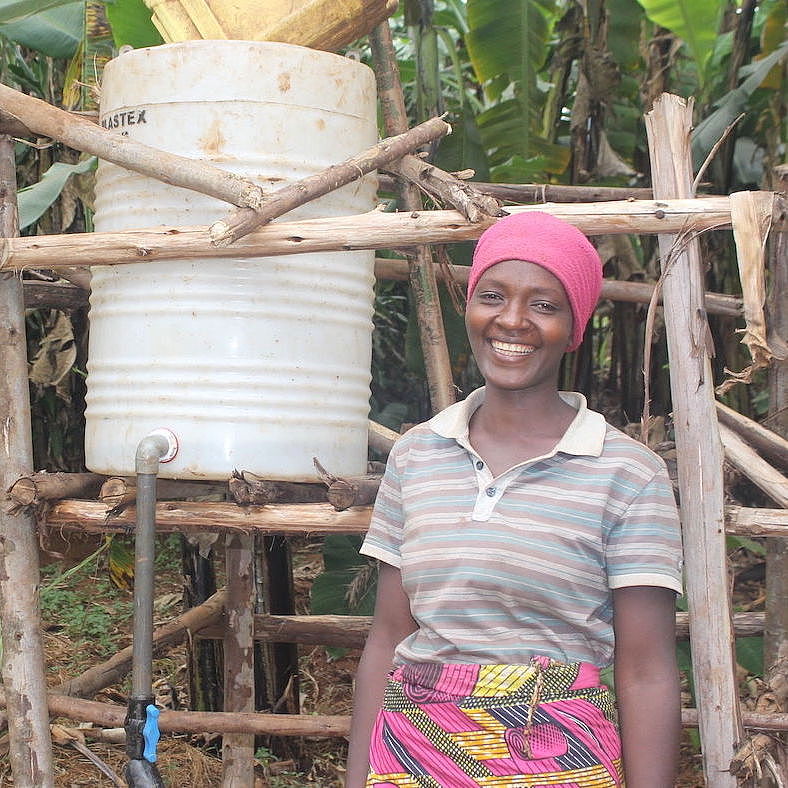 Eine Frau steht lächelnd neben einem selbsterrichteten System zur Bewässerung ihres Gartens