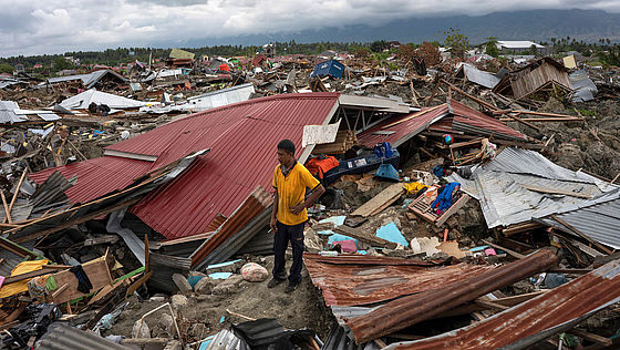Ein Mann steht inmitten der Trümmer, die der Tsunami in Indonesien 2018 hinterlassen hat