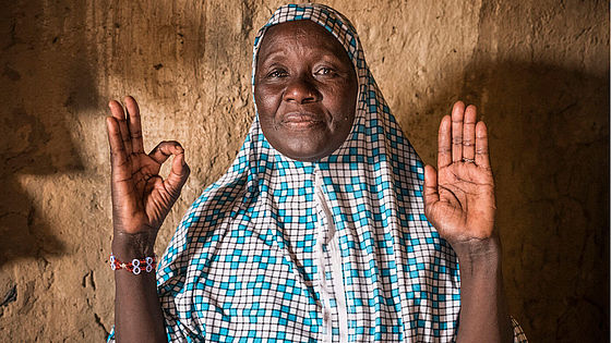 Haoua aus dem Niger macht mit ihren Händen das 1,5-Grad-Zeichen.