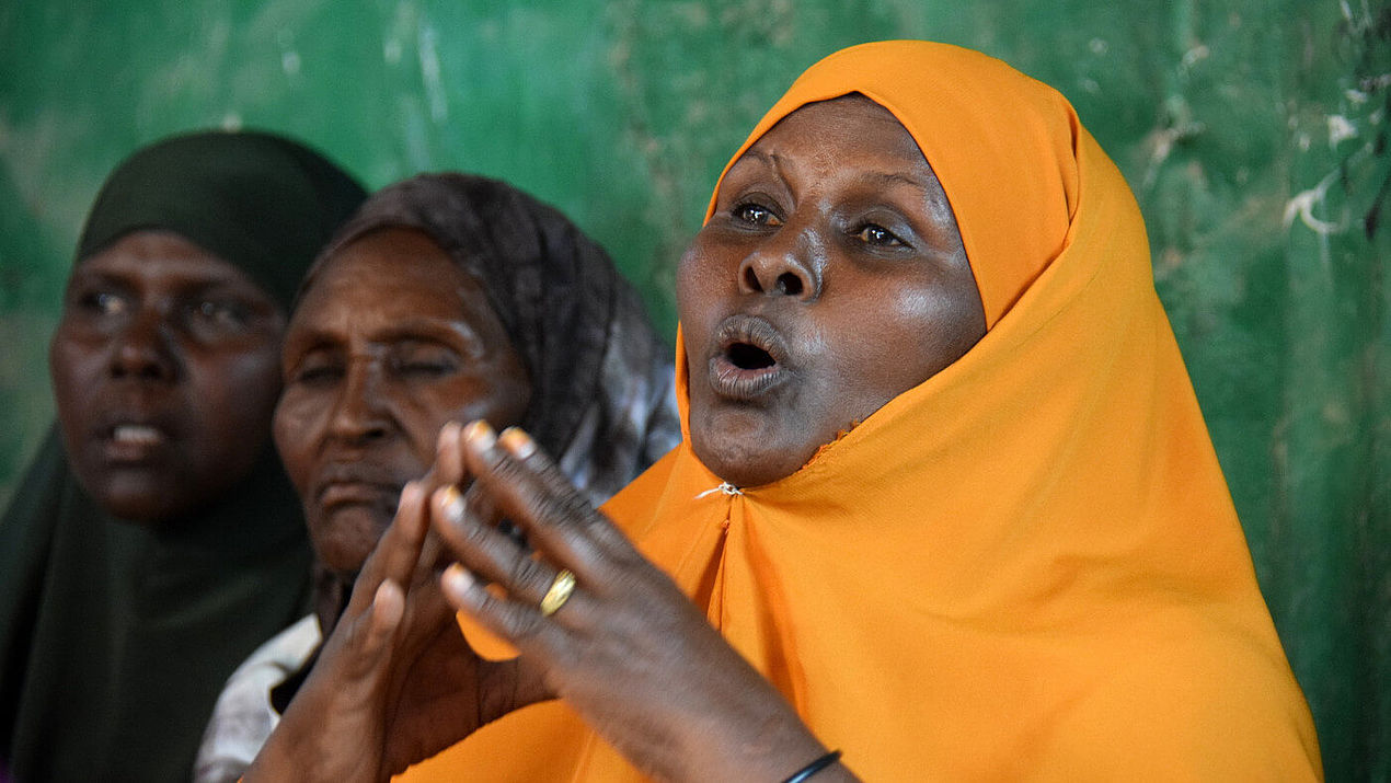 Eine Frau im gelben Gewand spricht bei einem Treffen einer CARE-Kleinspargruppe in Ainabo, Somalia.