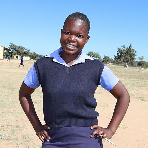 Das Mädchen Jennifer steht vor ihrer Schule, die sie dank der Unterstützung von CARE auch während ihrer Periode besuchen kann.