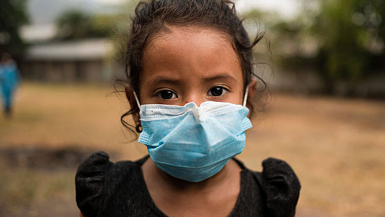 Ein Mädchen aus Honduras trägt eine medizinische Maske um sich gegen das Coronavirus zu schützen