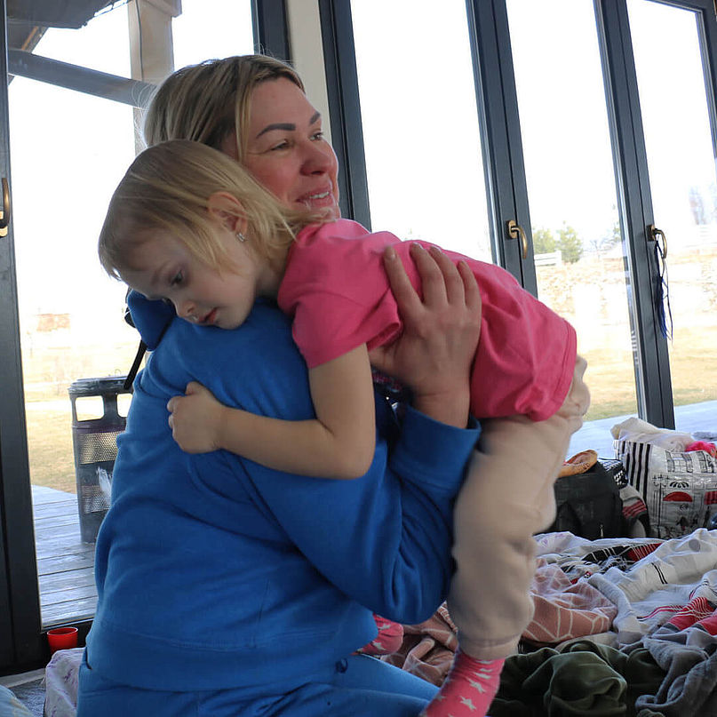 Olena umarmt ihre Tochter in der Unterbringung für ukrainische Vertriebene