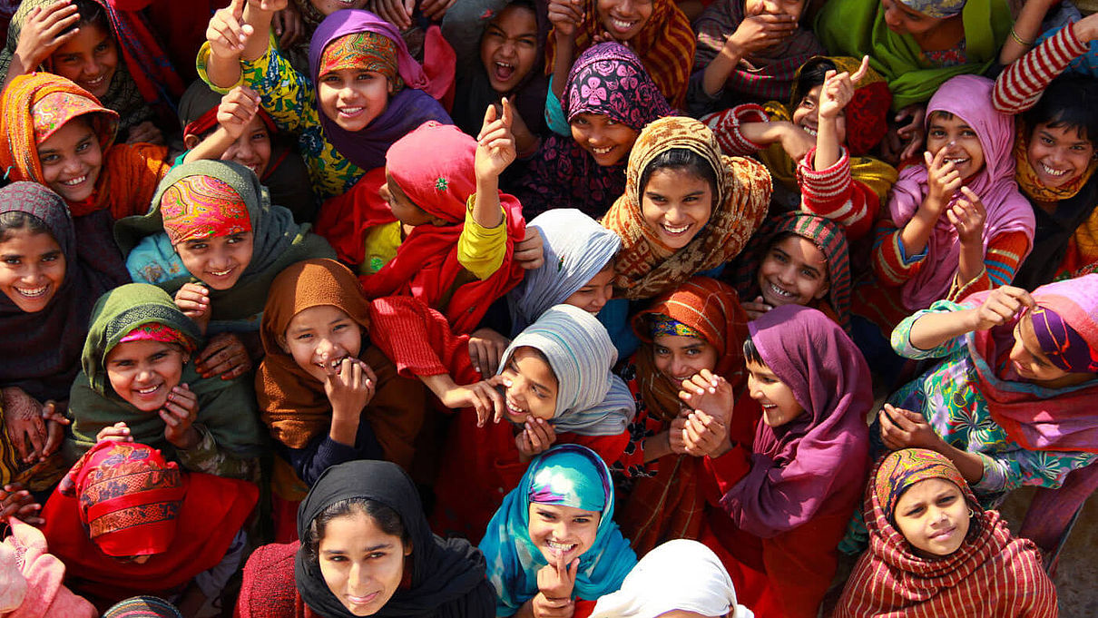 Eine Gruppe indischer Mädchen in bunter Kleidung steht zusammen und lacht