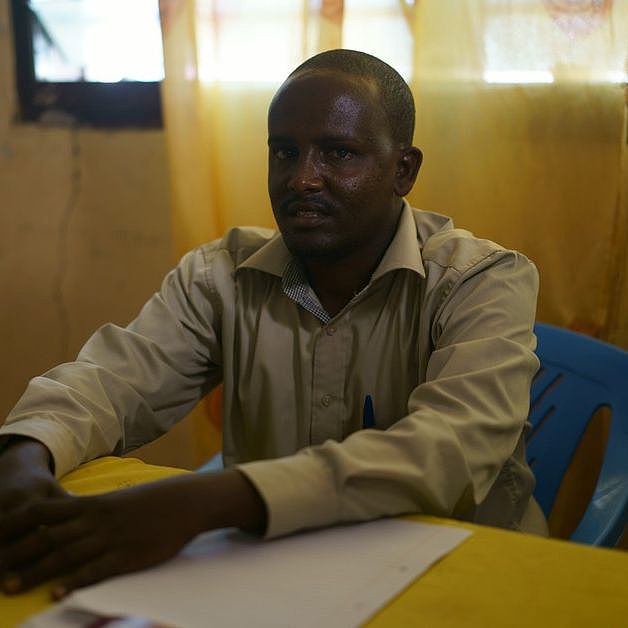 Der Lehrer Ibrahim Ali Mohamed sitzt an einem Tisch im Flüchtlingscamp Dadaab in Kenia.