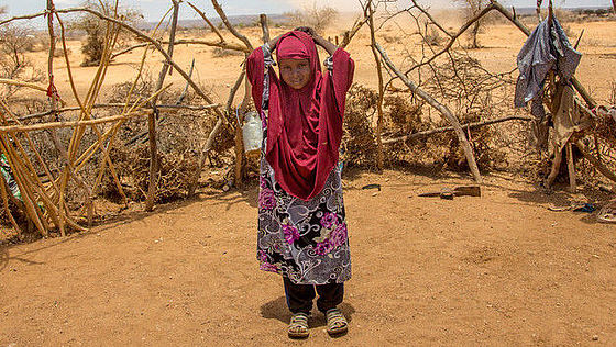 Ein Mädchen in bunter Kleidung steht in einer Wüstenlandschaft