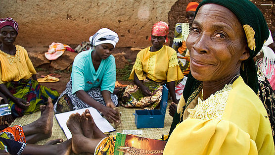 Eine Teilnehmerin einer CARE-Spargruppe in Burundi, im Hintergrund sind andere Teilnehmerinnen zu sehen