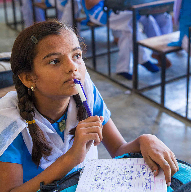 Ein 12-jähriges Mädchen in Schuluniform hört im Unterricht aufmerksam zu