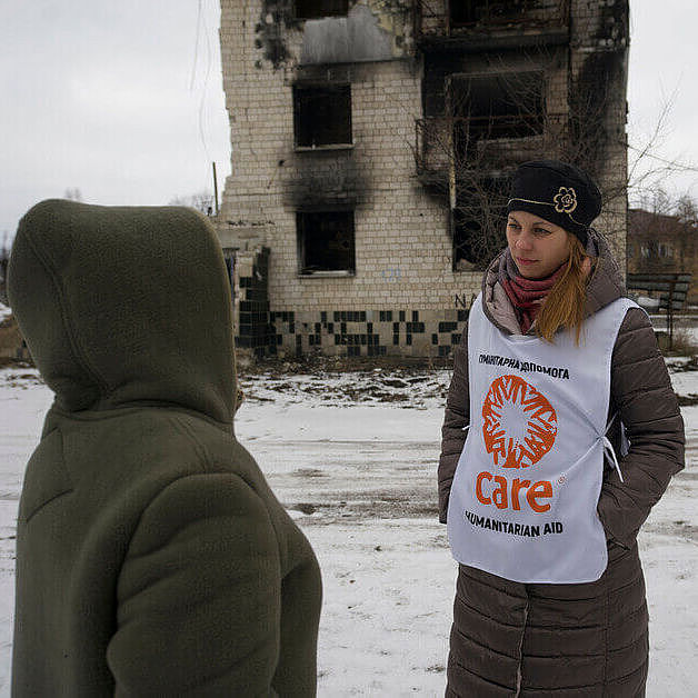 Daria und eine andere Frau vor einem zerbombten Haus im kalten Winter während des Krieges in der Ukraine