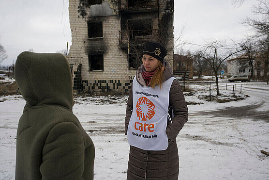 Daria und eine andere Frau vor einem zerbombten Haus im kalten Winter während des Krieges in der Ukraine