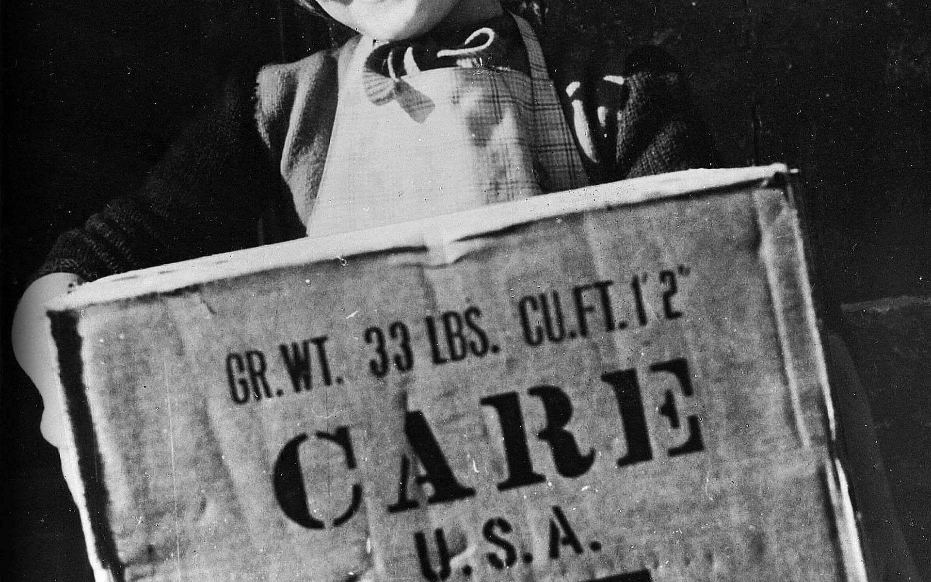 Ein Mädchen hält ein CARE-Paket in ihren Händen.