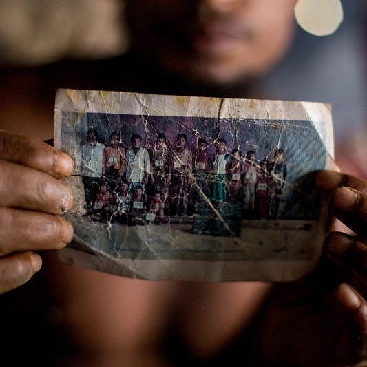 Ein Mann hält das letzte Foto seiner Frau und seiner Familie in die Kamera.