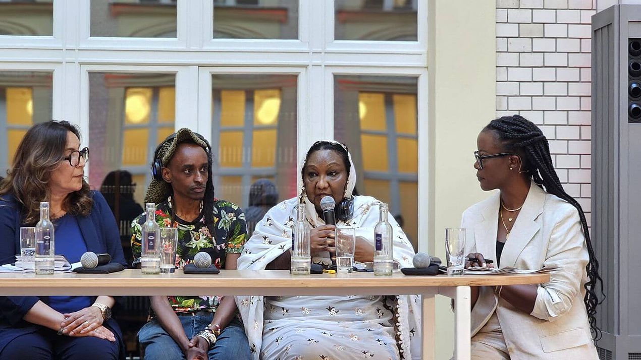 Fatima auf Panel Fatima sitzt mit drei weiteren Personen auf einem Panel.