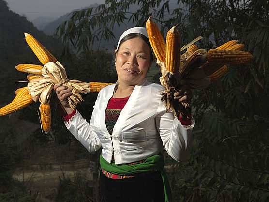 Eine Frau präsentiert ihre Maisernte