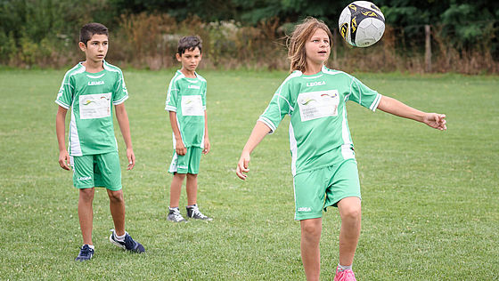 Drei Kinder spielen Fußball in Bosnien