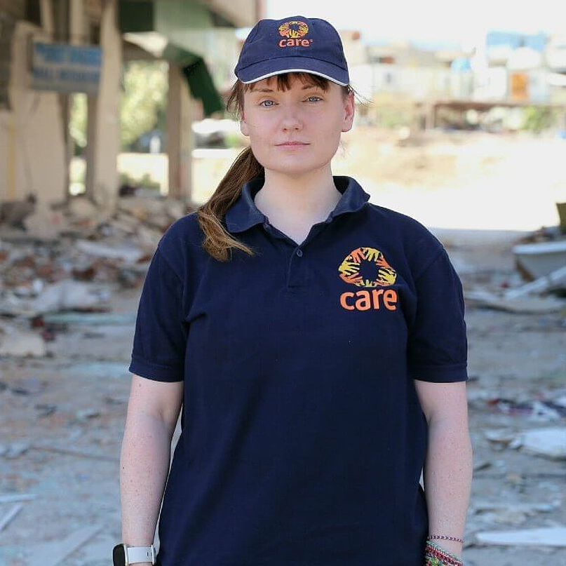 CARE-Mitarbeiterin Sarah steht in einer vom Erdbeben zerstörten Stadt.