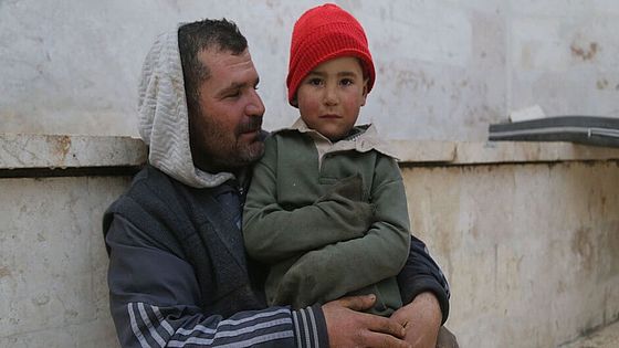 Vertriebener in Idlib, Syrien hält seinen Sohn im Arm