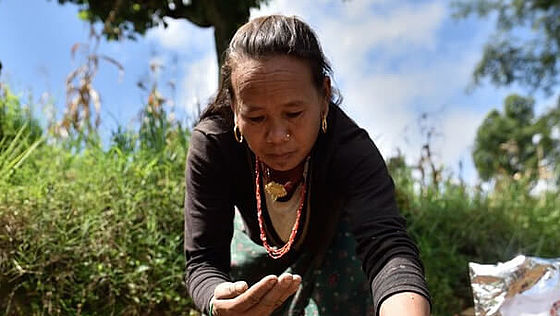 Eine Frau in Nepal pflanzt von CARE bereitgestellte Gemüsesamen auf ihrem Feld