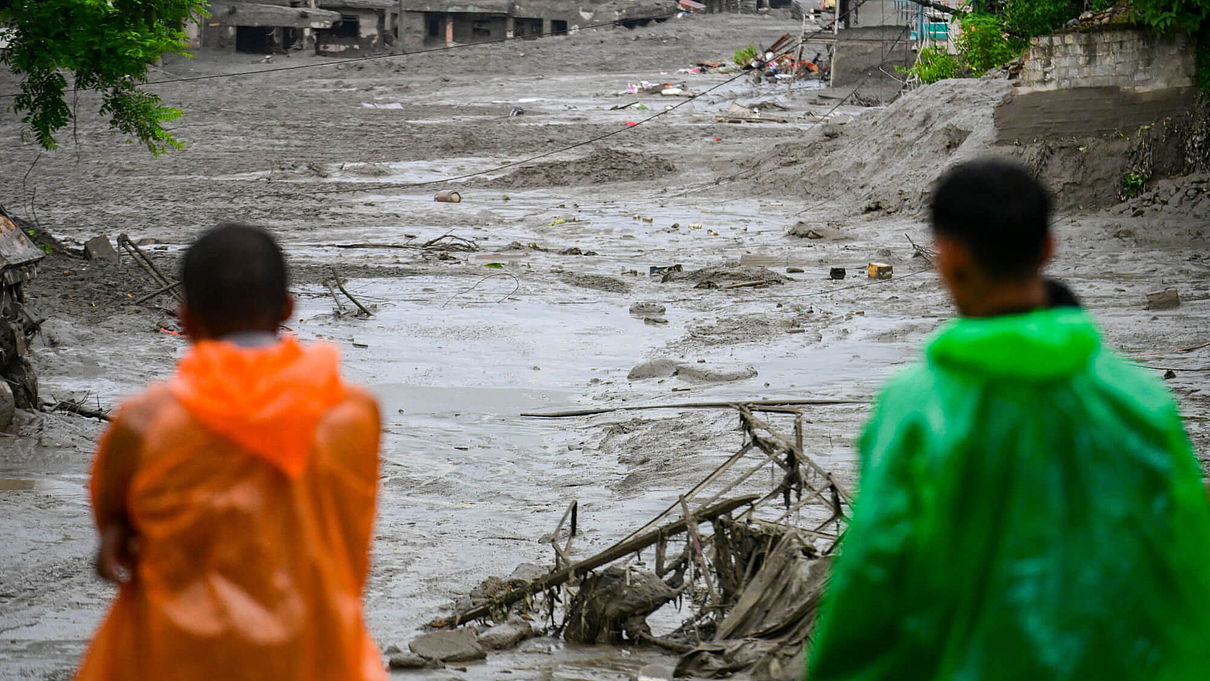 Zwei Männer blicken auf die Zerstörung nach der Sturzflut in Nepal 