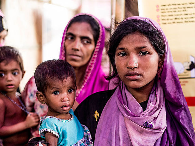 Hamida hält ihre mangelernährte Schwester auf dem Arm. Im Flüchtlingscamp in Bangladesch trägt Hamida ihre mangelernährte Schwester Bushra auf dem Arm.