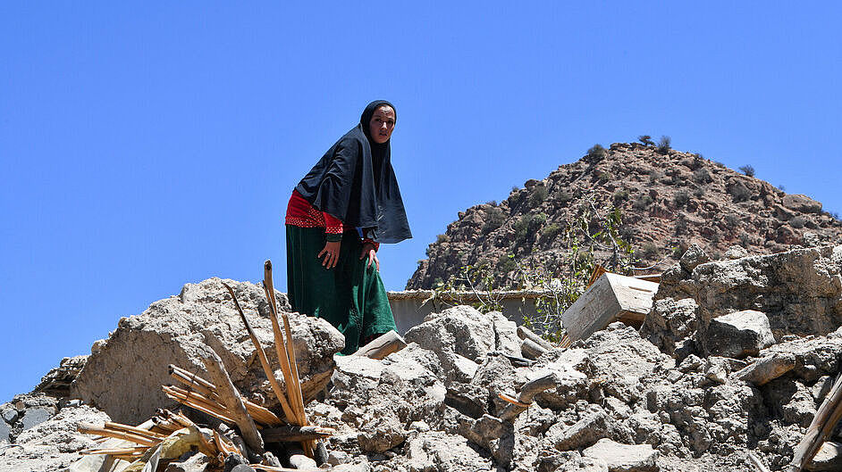 Frau steht auf den Trümmern ihres Hauses nach den Erdbeben in Marokko.
