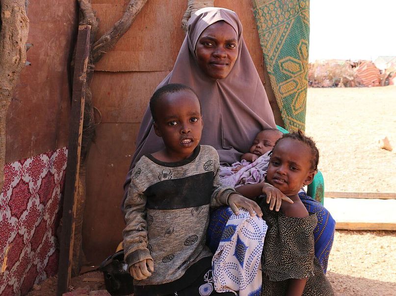 Khadra mit drei ihrer Kinder Khadra sitzt mit drei ihrer Kinder vor ihrer Unterkunft.